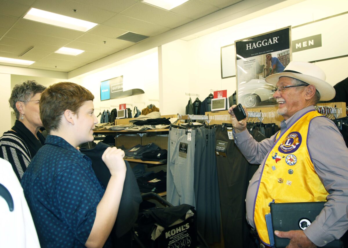 A boy shows pants to a Lions Club member who is taking his picture.