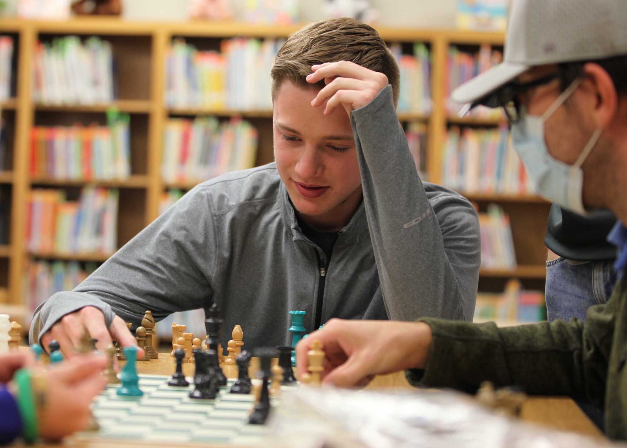 A boy plays four-sided chess with friends.