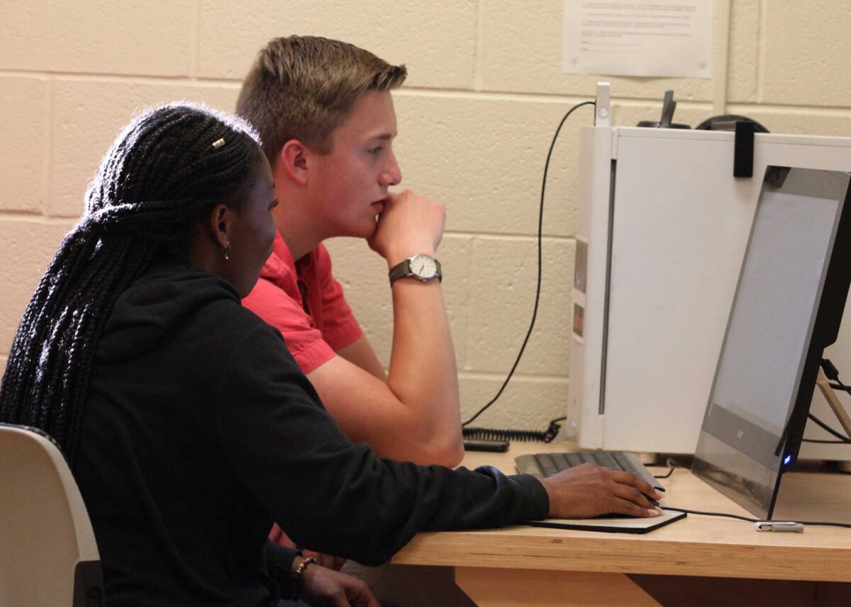 A woman and boy work at a computer