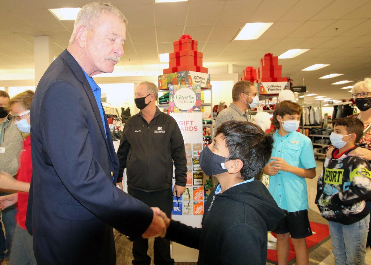 A boy and a tall man shake hands.