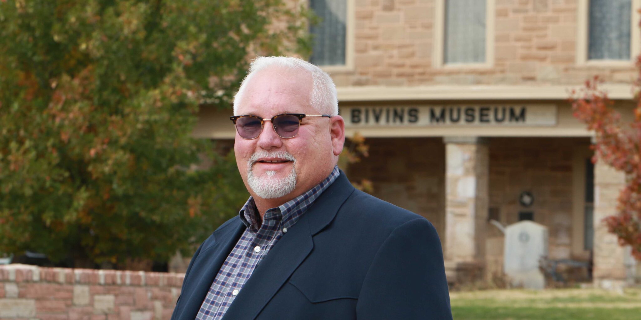 A man with white hair stands in front of Julian Bivins museum.