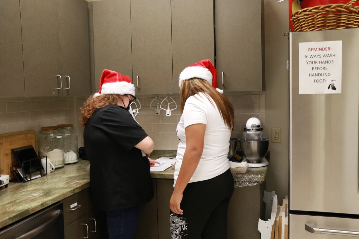 Two women look at a recipe in a kitchen.