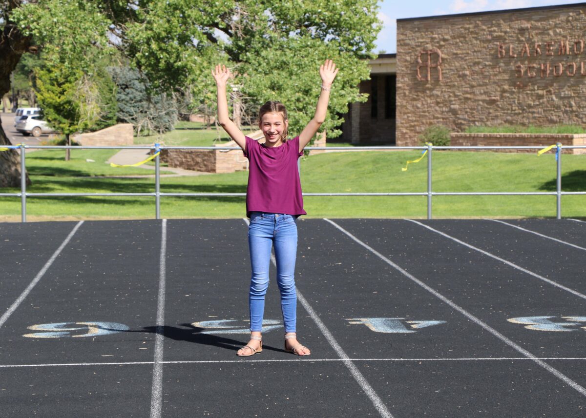 a girl raises her arms at the end of a track.