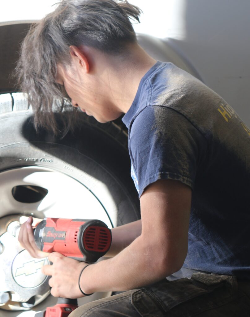 A boy holds a drill to a tire.