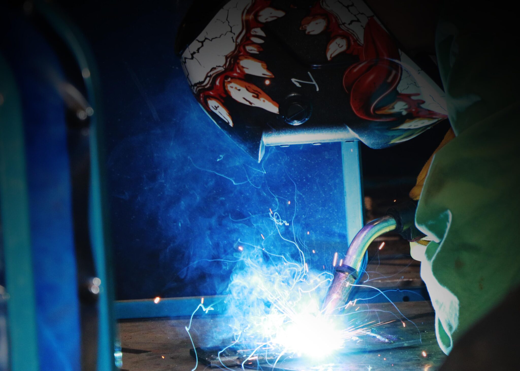 A welder works in a blue light.
