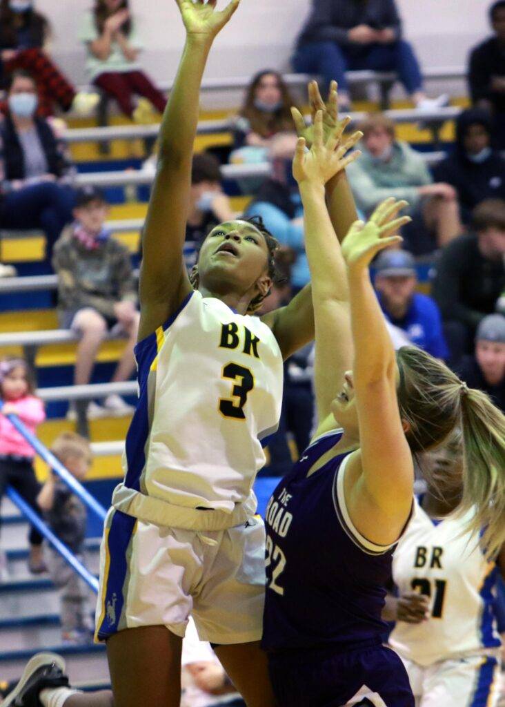 A girl goes up to shoot a basketball.