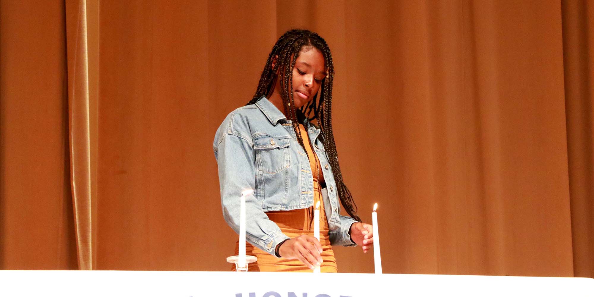 A girl lights candles on a National Honor Society table