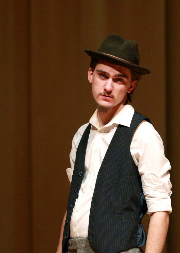 A teenager wears a hat for a role in a play