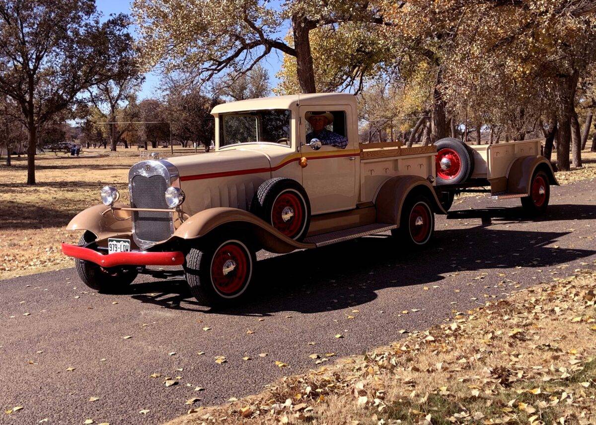 A man drives an old-fashioned car down a Boys Ranch road.