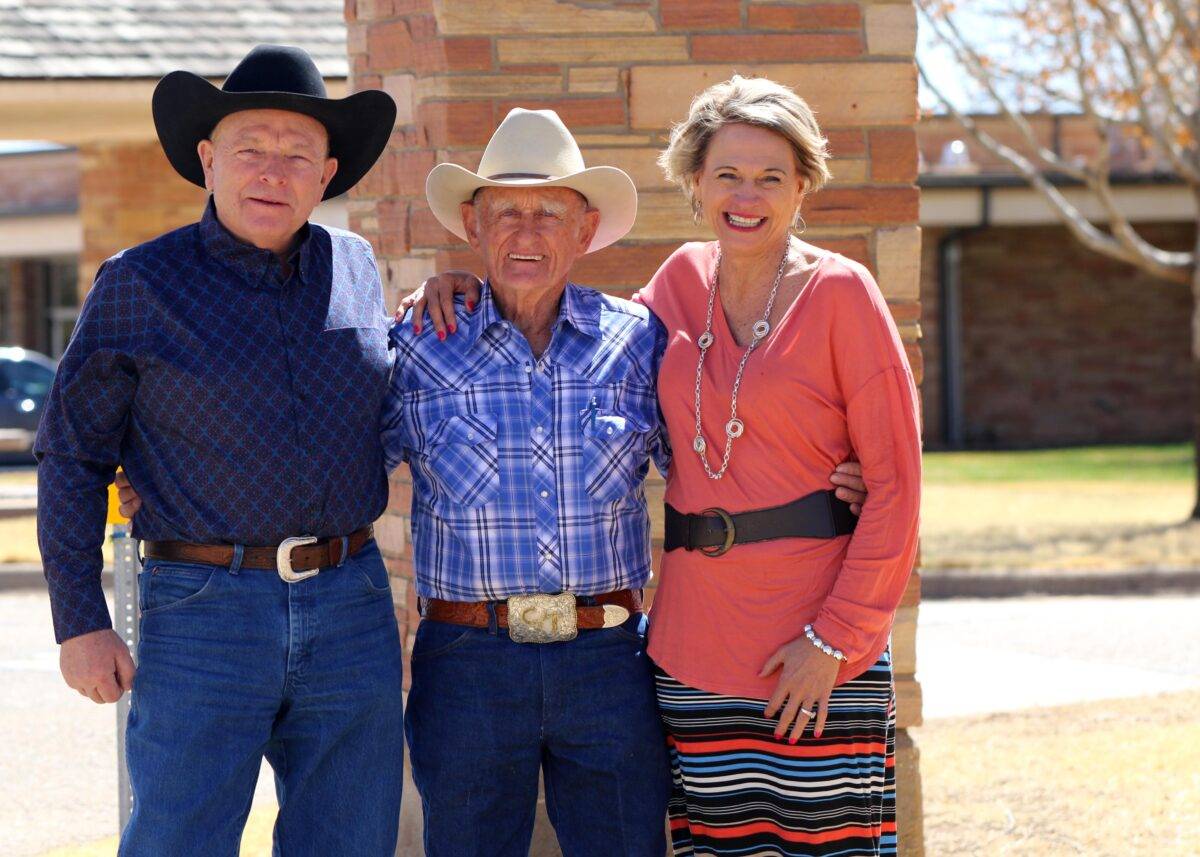 Two men and a woman stand in front of a pillar