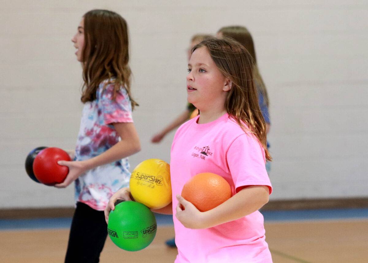 Two girls gather balls for a game of dodgeball.