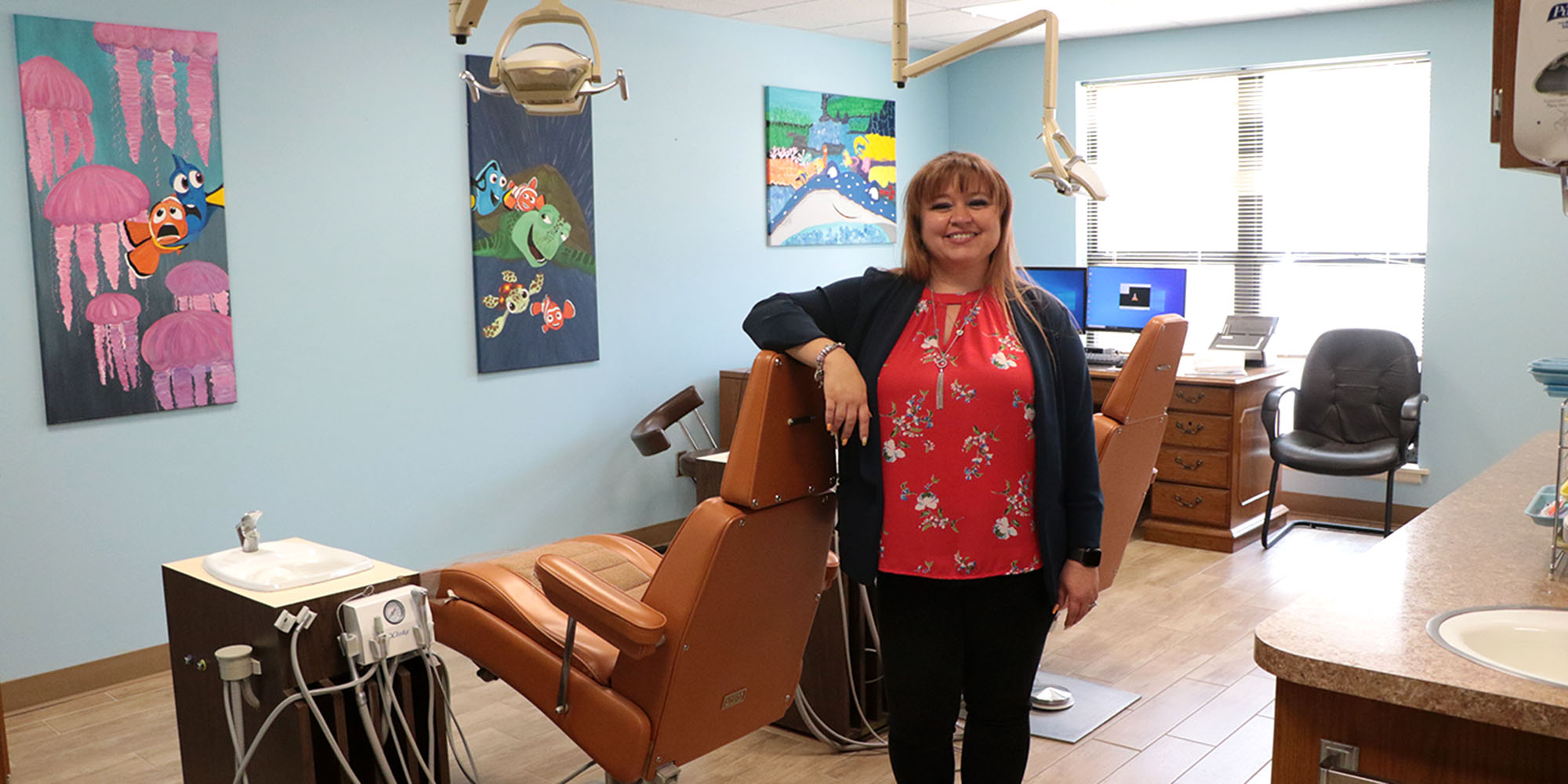 a woman stands in a dentist's office.