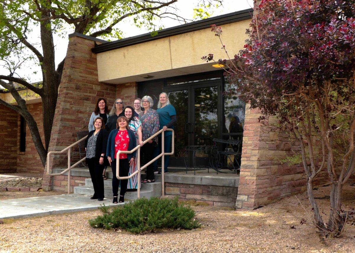 Healthcare professionals stand in front of a clinic.