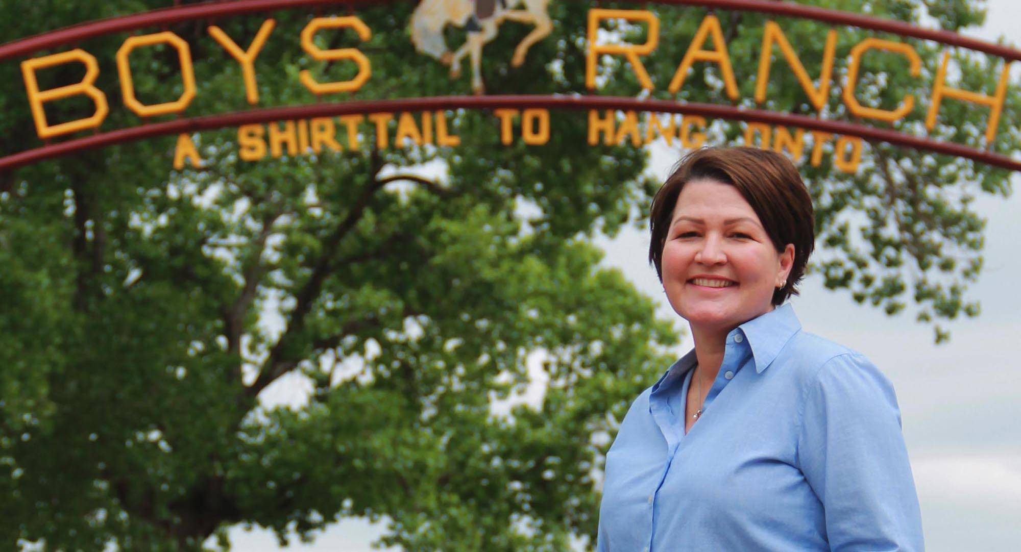 Michelle Maikoetter stands in front of the Boys Ranch entrance gate.