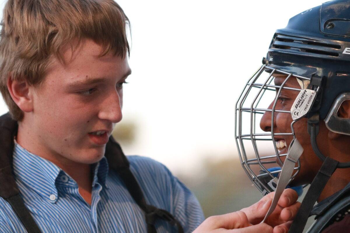 James helps Nate fit his helmet before a bronc ride.