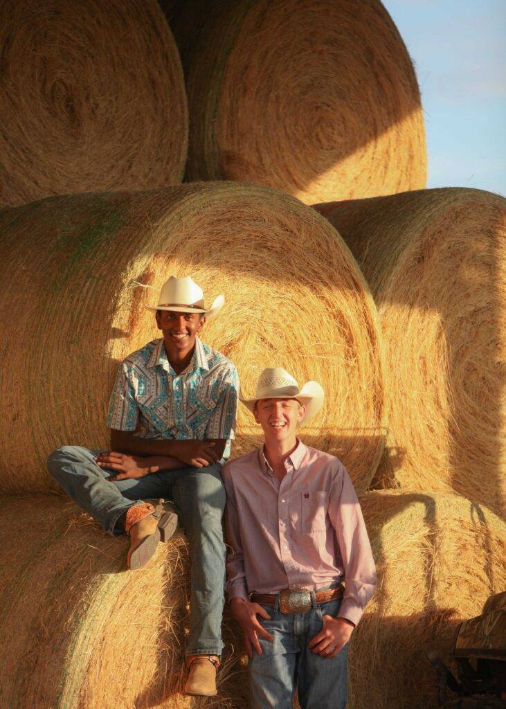 James and Nate sit on hay bales and share a laugh.