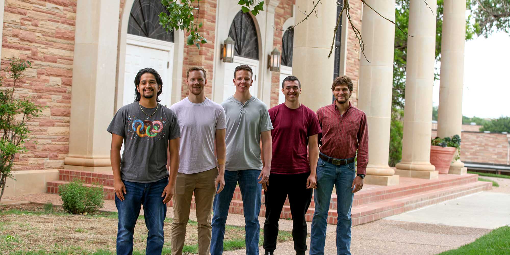 Five young men stand in front of the chapel