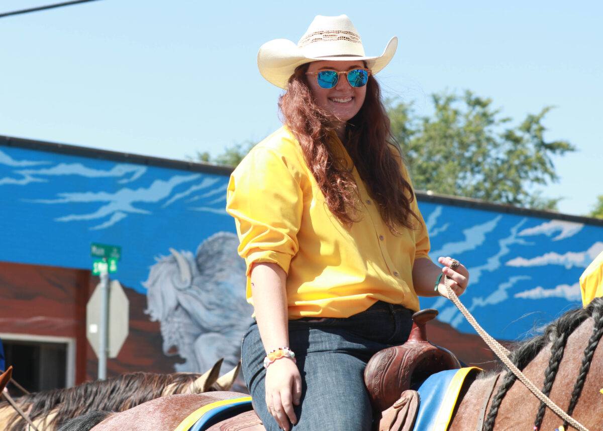 Sarah rides a horse in a parade.