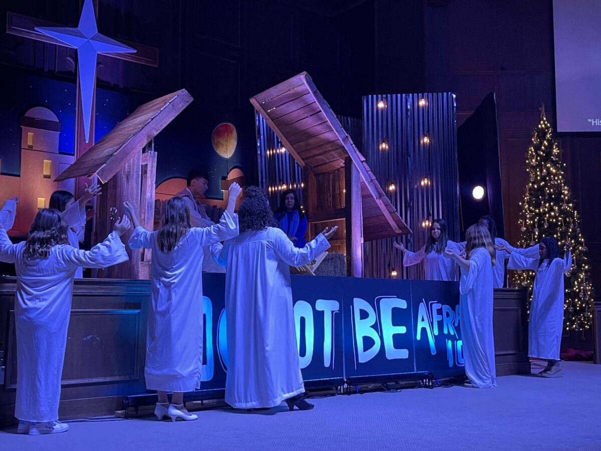 Girls dressed as angels surround a manger scene.